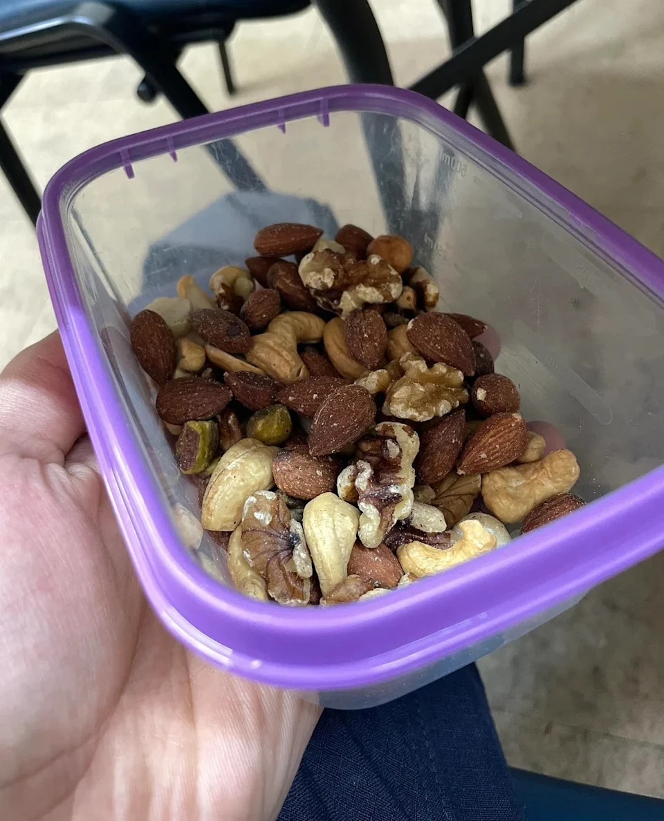 Mixed nuts including almonds, cashews, walnuts, and pistachios in a clear plastic container