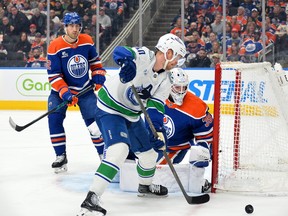 Connor Ingram and Evan Bouchard of the Edmonton Oilers track the puck against Elias Pettersson during the first period