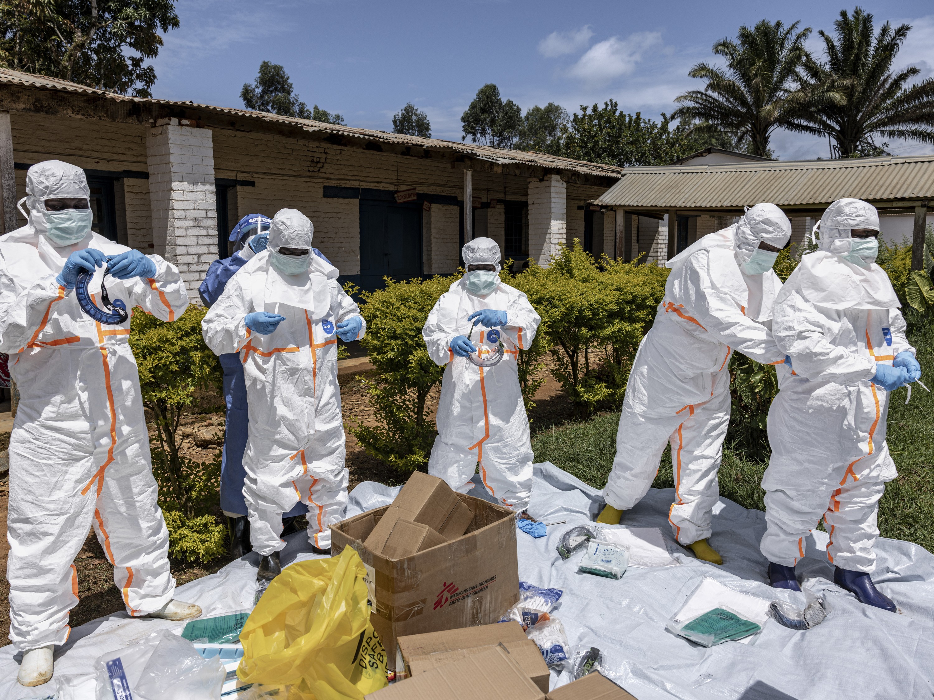 Several health workers put on full-body personal protective equipment.
