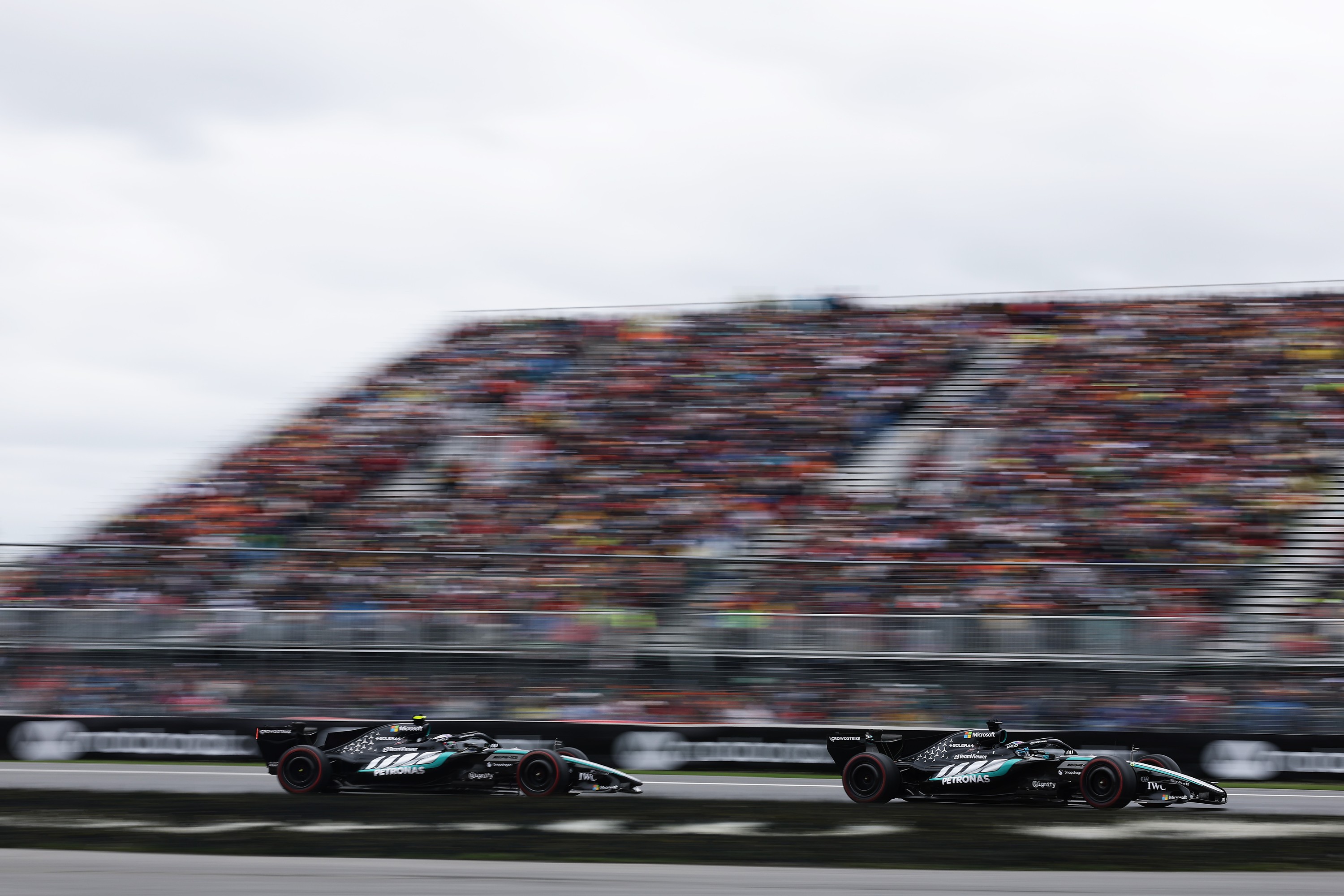 Two race cars on a track against a blurred background of fans in stands.