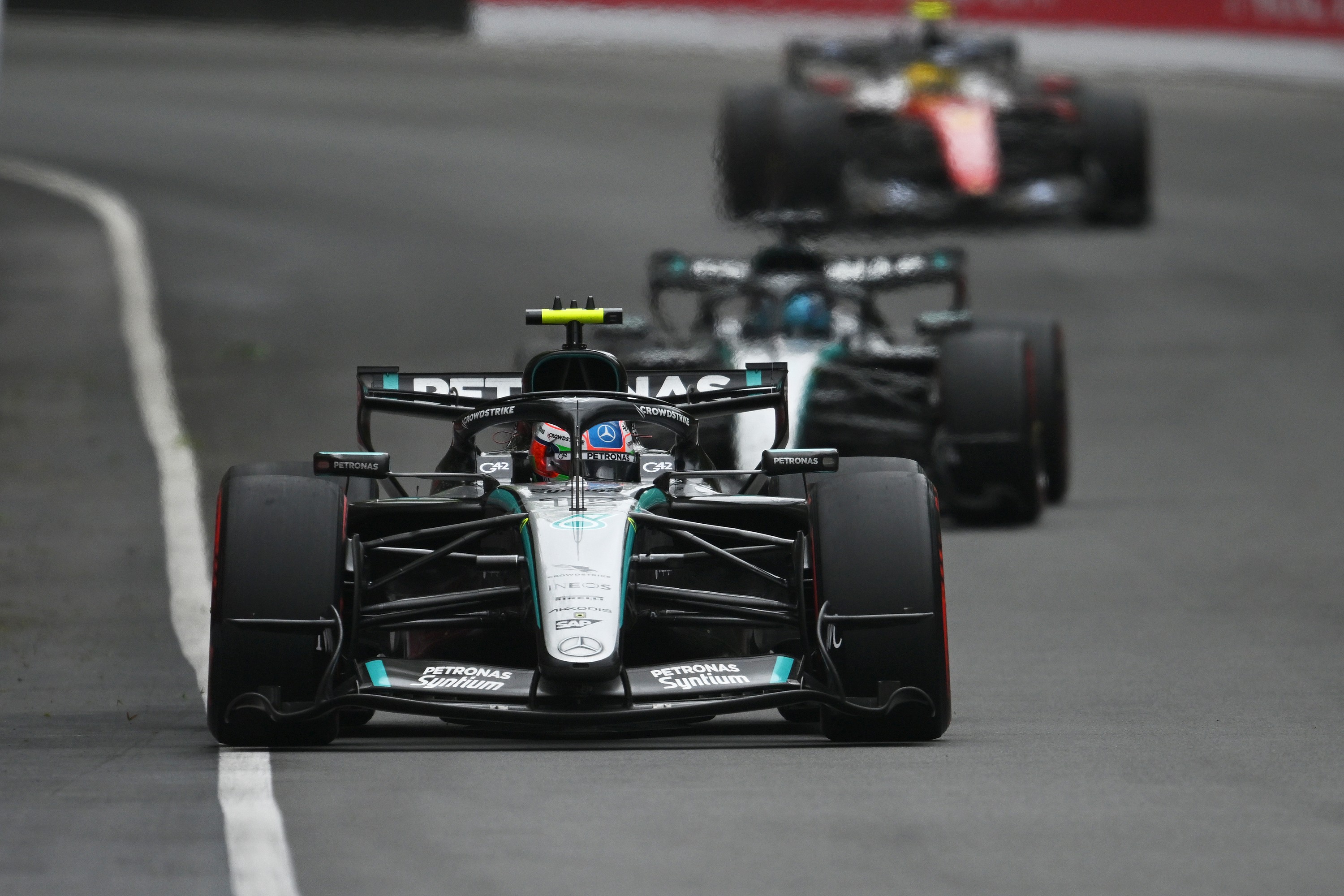 Three race cars on a Grand Prix track, with Petronas in the lead.