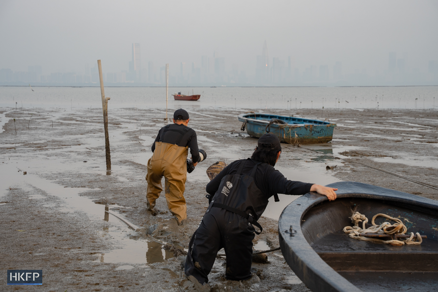 Fung Hon-shing and a friend wade through mud to photograph migratory birds at a remote shore in Yuen Long on March 25, 2026. Photo: Kyle Lam/HKFP.