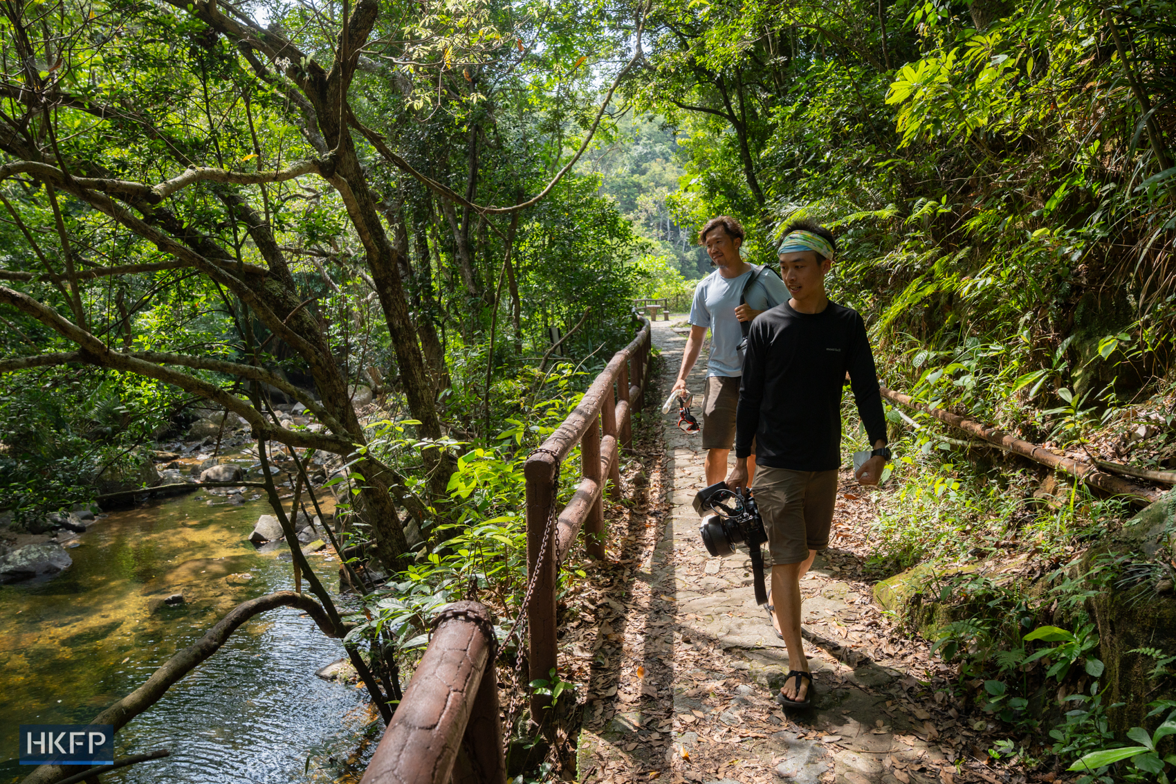Fung Hon-shing (front) and his colleague James Kwok hike to a stream in Tai Po with underwater filming equipment on July 9, 2025. Photo: Kyle Lam/HKFP.