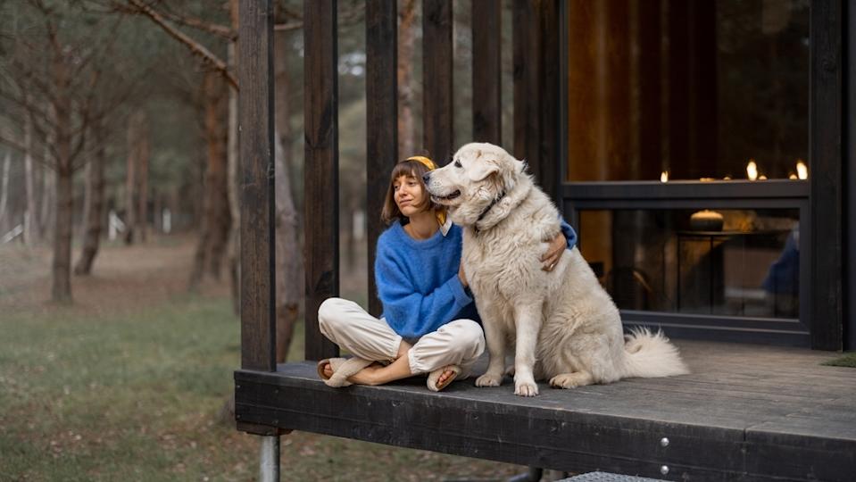 Young woman sitting on cottage porch with dog