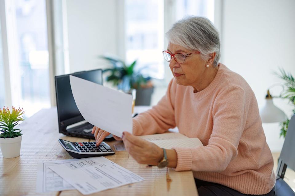 Person sitting at a kitchen table while using a calculator. 