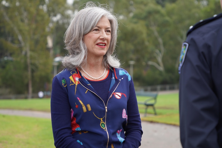 nicola spurrier speaks with a man in police uniform in a park