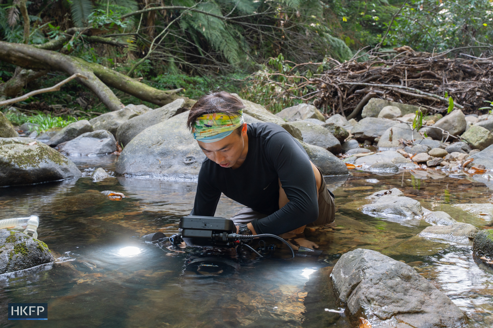 Fung Hon-shing shoots with underwater filming equipment at a stream in Tai Po on July 9, 2025. Photo: Kyle Lam/HKFP.