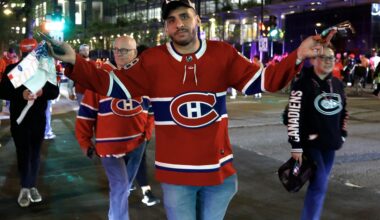A man in a Canadiens jersey shrugs as he crosses the street at night.
