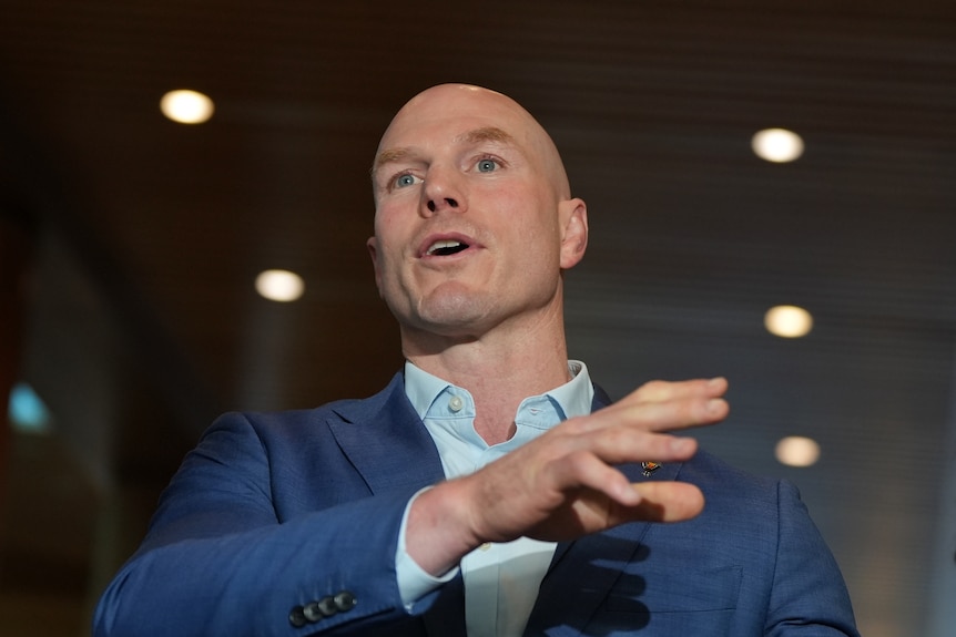 A politician in a blue shirt and blazer speaks animatedly.