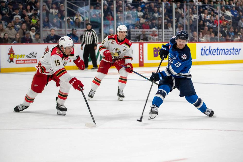 BROOK JONES/FREE PRESS
Manitoba Moose right-winger Mason Shaw shoots the puck while Grand Rapids Griffins left-winger John Leonard tries to block it during second period action Saturday in Winnipeg.