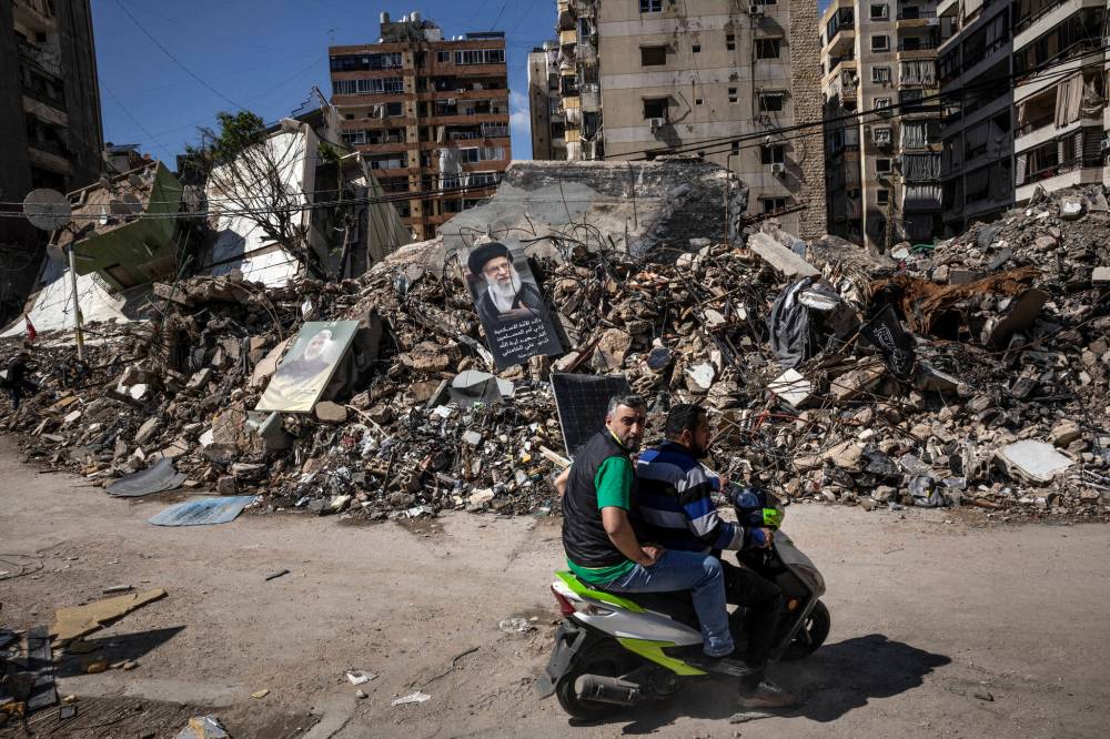 The New York Times / File
Men pass a poster of Ayatollah Ali Khamenei, the late supreme leader of Iran, on a pile of rubble from Israeli airstrikes.
