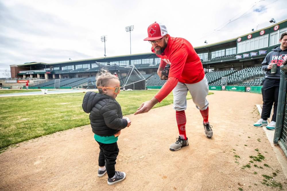 MIKAELA MACKENZIE / FREE PRESS
Pitcher Mitch Lambson warms up with his 19-month-old son, Kolby, at practice on Wednesday. Lambson is one of the Winnipeg Goldeyes’ “core four” who have made Winnipeg their full-time home.