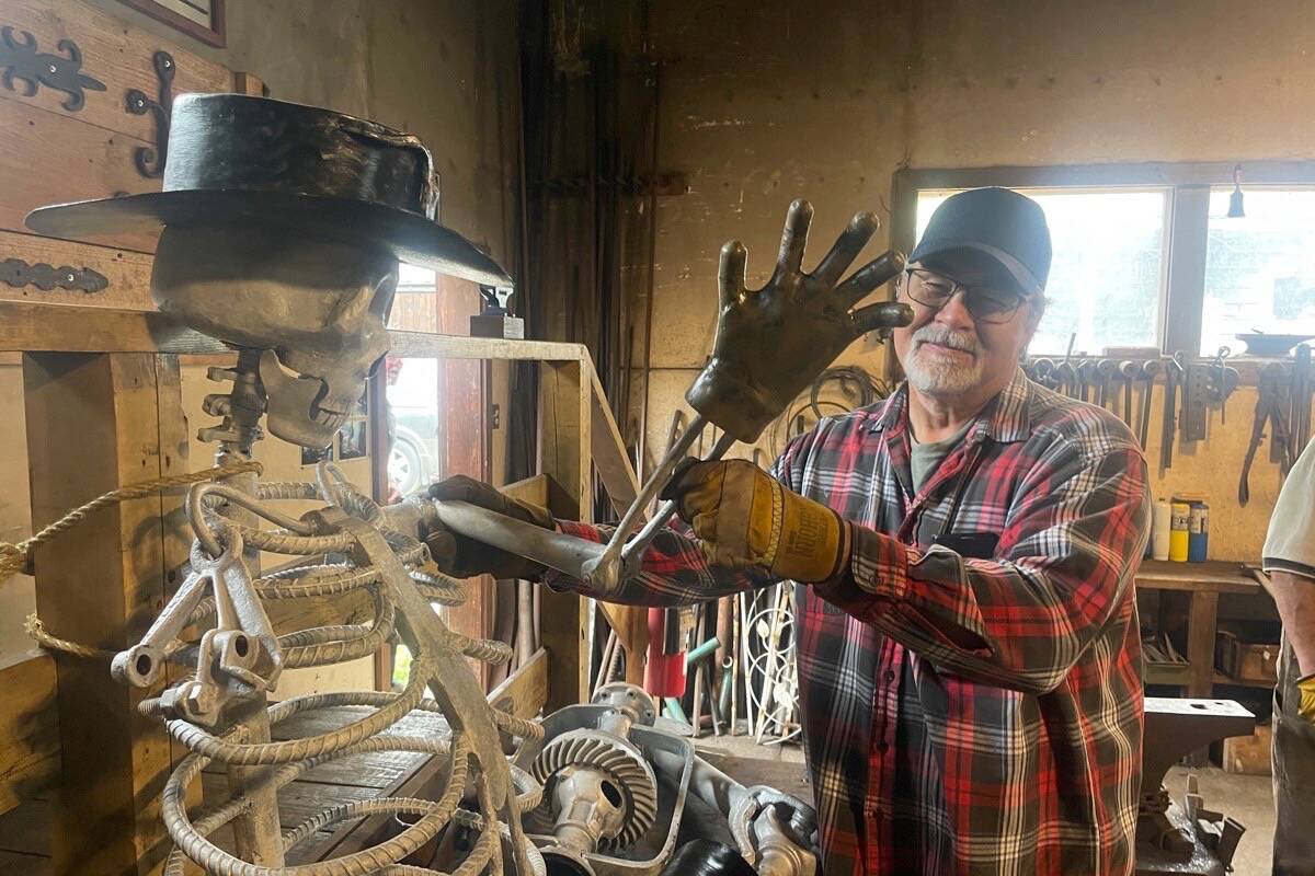 Doug Philp with the figure, made of fully reused materials, forged in the blacksmith shop that will sit atop the tractor greeting guests to Heritage Acres in Central Saanich this season. (Christine van Reeuwyk/Peninsula News Review)