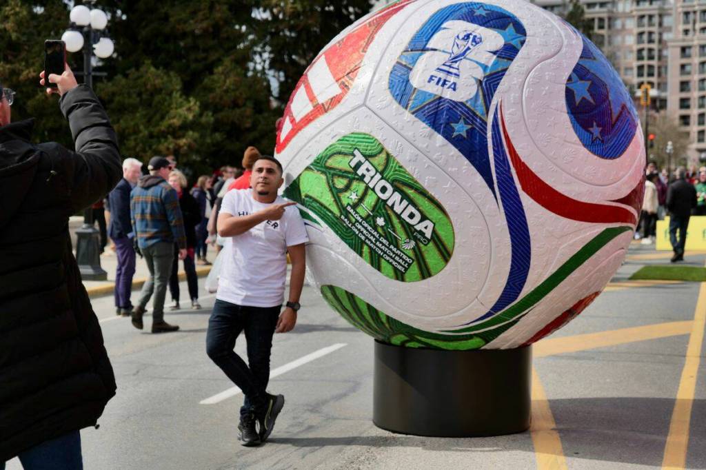 A fan snaps a photo alongside a giant soccer ball display outside the B.C. legislature during the Canada Celebrates test event on Tuesday. (Tony Trozzo/Victoria News)