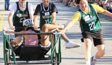 A runner on the Lord Tweedsmuir racing team ended up on top of the squad&rsquo;s bed-race rider in 2023 after he performed a &ldquo;miraculous endo.&rdquo; The runner tripped and miraculously bounced up and flipped up into the car, thus avoiding being run over by the bed. (Photo: Malin Jordan)