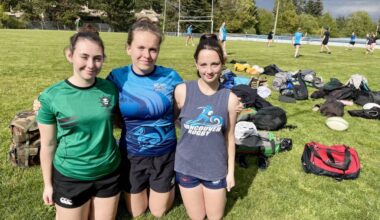 Grade 12 students Cooper Marsden, left, Astrid Maynes and Isla Van Staveren pose for a photo as their Earl Marriott Secondary girls rugby team starts practice in the background. The Mariners squad has started out their season 3-0 so far. (Tricia Leslie photo/Peace Arch News)