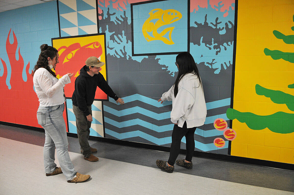 Artist Josh Conrad, seen here with Indigenous support workers Caitlin Demmitt (left) and Kristie Peters, painted this mural inside Shxwelis te Ts’qó:ls (Spirit of Hope Secondary School). They are pictured on April 10, 2026. (Jenna Hauck/ Hope Standard)