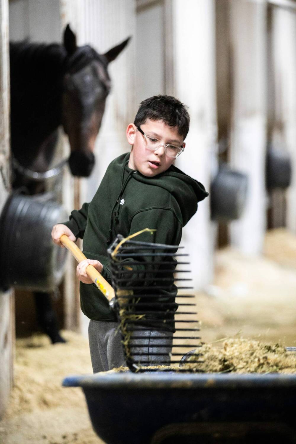 MIKAELA MACKENZIE / FREE PRESS
Kenner Keplin, eight, pitches in at his dad’s barn by mucking out stalls.