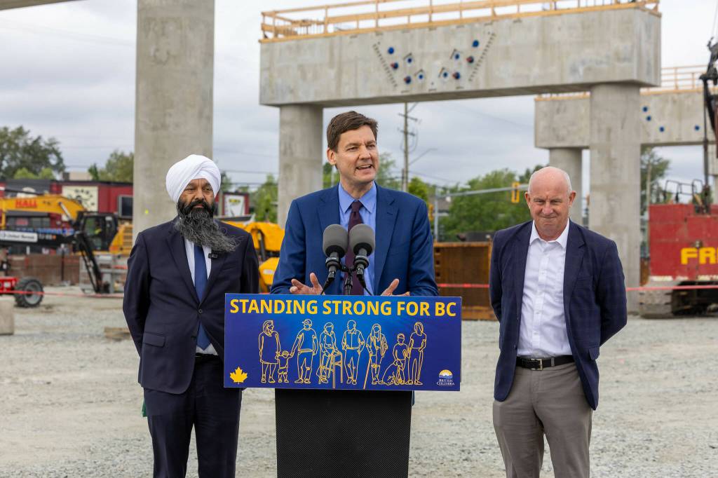 Premier David Eby, at microphone, was joined by Surrey Centre MP Randeep Sarai and B.C. Minister of Transportation and Transit Mike Farnworth at a May 8 event marking the progress of the Surrey Langley SkyTrain project, at the site of the future Willowbrook station on the Langley-Surrey border. (B.C. Government/Flickr)
