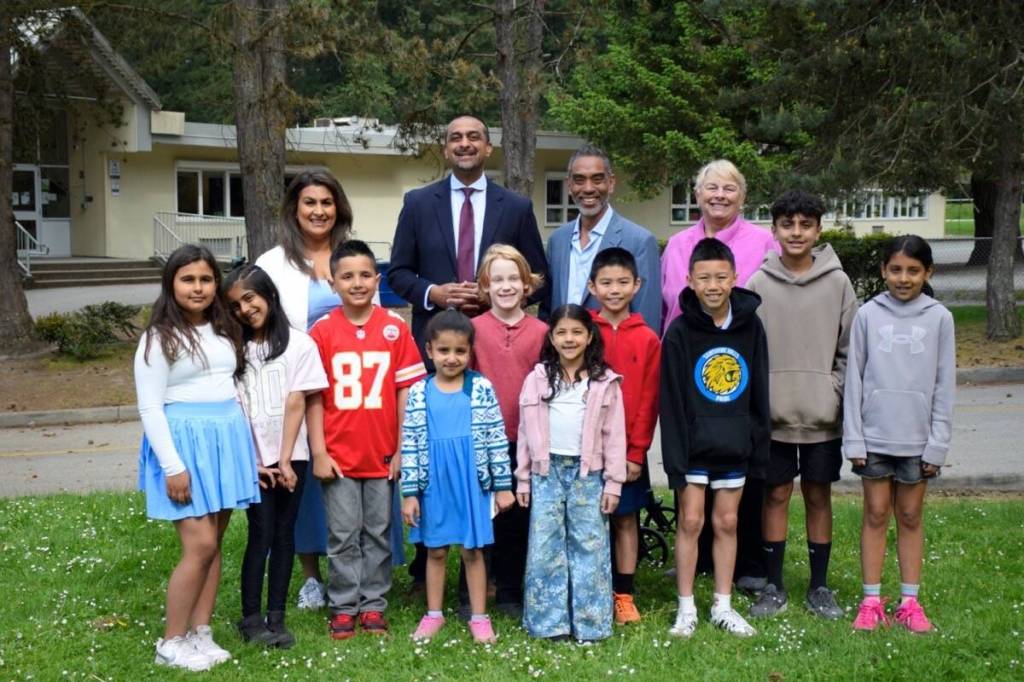 PAC co-chair Joyt Uppal, Delta North MLA Ravi Kahlon, school board chair Joe Muego and trustee Val Windsor, back row from left, pose with students outside Sunshine Hills Elementary on Friday, May 8, after the province announced $200,000 to replace the North Delta school&rsquo;s 35-year-old playground. (James Smith/North Delta Reporter photo)