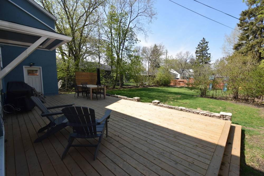 A huge deck with a barbecue area and seating overlooks the park-like backyard.