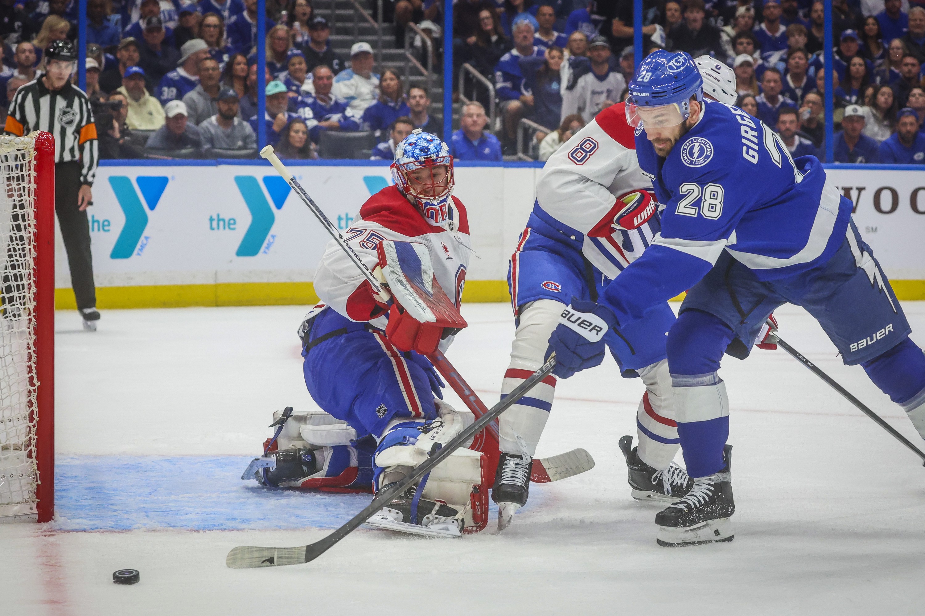 Montreal Canadiens goaltender Jakub Dobes watches as Tampa Bay Lightning centre Zemgus Girgensons attempts to gather the puck while holding off Canadiens defenceman Mike Matheson