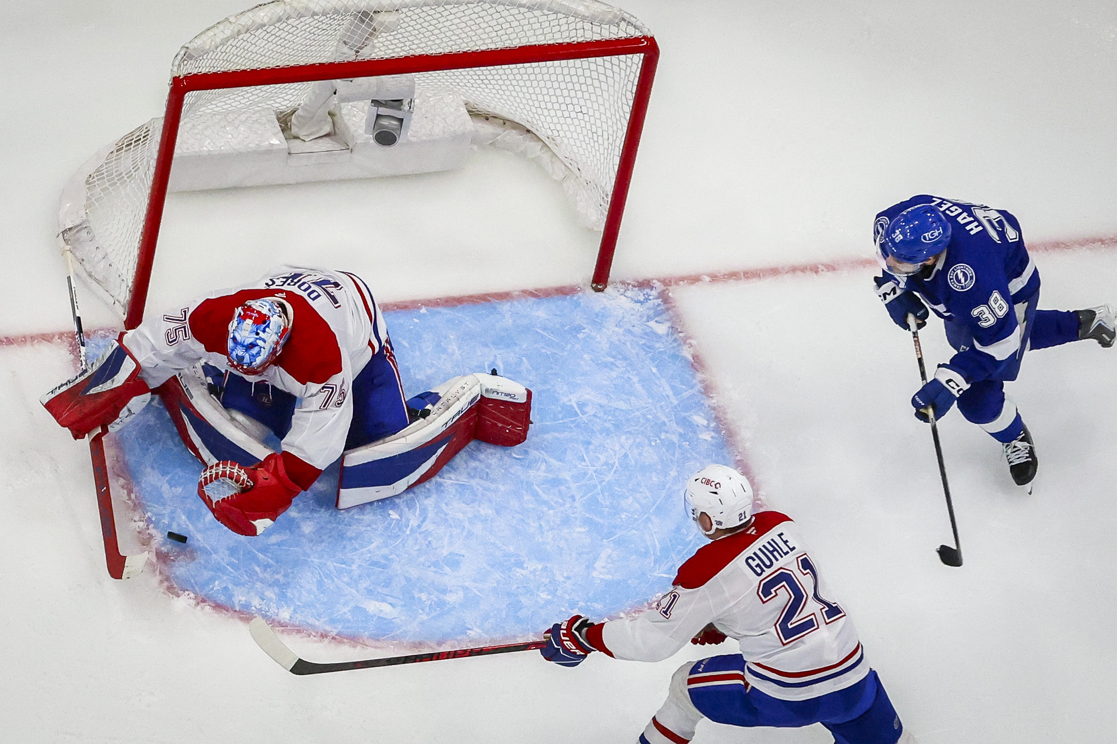 Montreal Canadiens goaltender Jakub Dobes looks to cover the puck as Brandon Hagel and Canadiens defenceman Kaiden Guhle look on