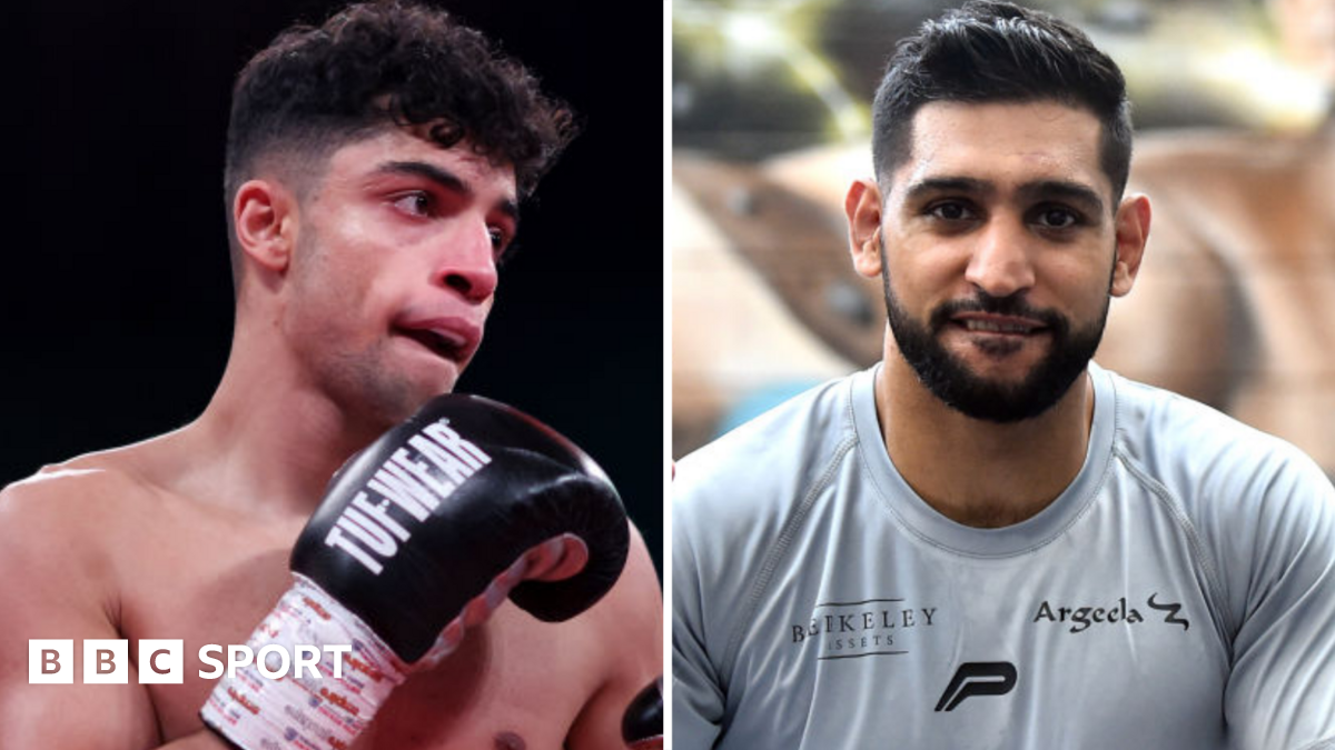 Abdul Khan (left) holds up his hand is wearing a black boxing glove and Amir Khan (right) is wearing a grey t-shirt