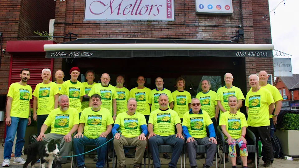 A group of 20 men and women, who are wearing matching yellow T-shirts with the walking route on them, have gathered together for a photograph.