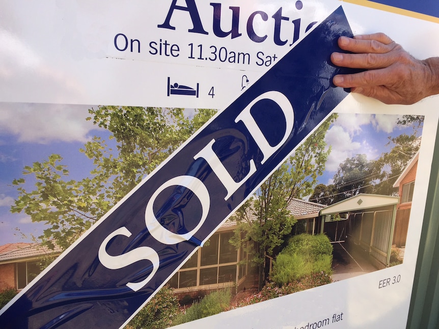 A sold sticker on a real estate listing board.