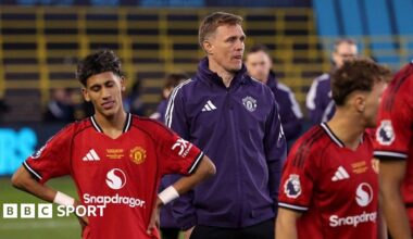 Manchester United Under-18 coach Darren Fletcher, in purple tracksuit top, stands between two of his players, who both wear red match kit