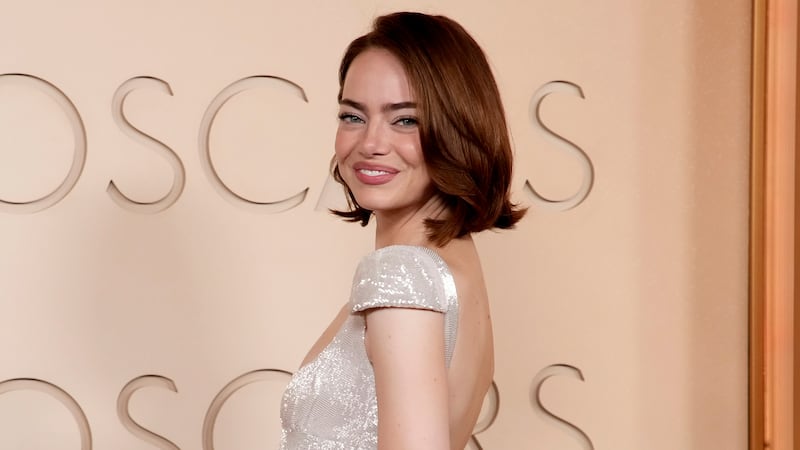 Emma Stone smiles on the 2026 Oscars red carpet. She did not walk the Vanity Fair gray carpet.