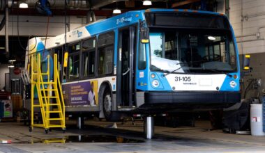 An STM bus sits on a hoist in a garage.