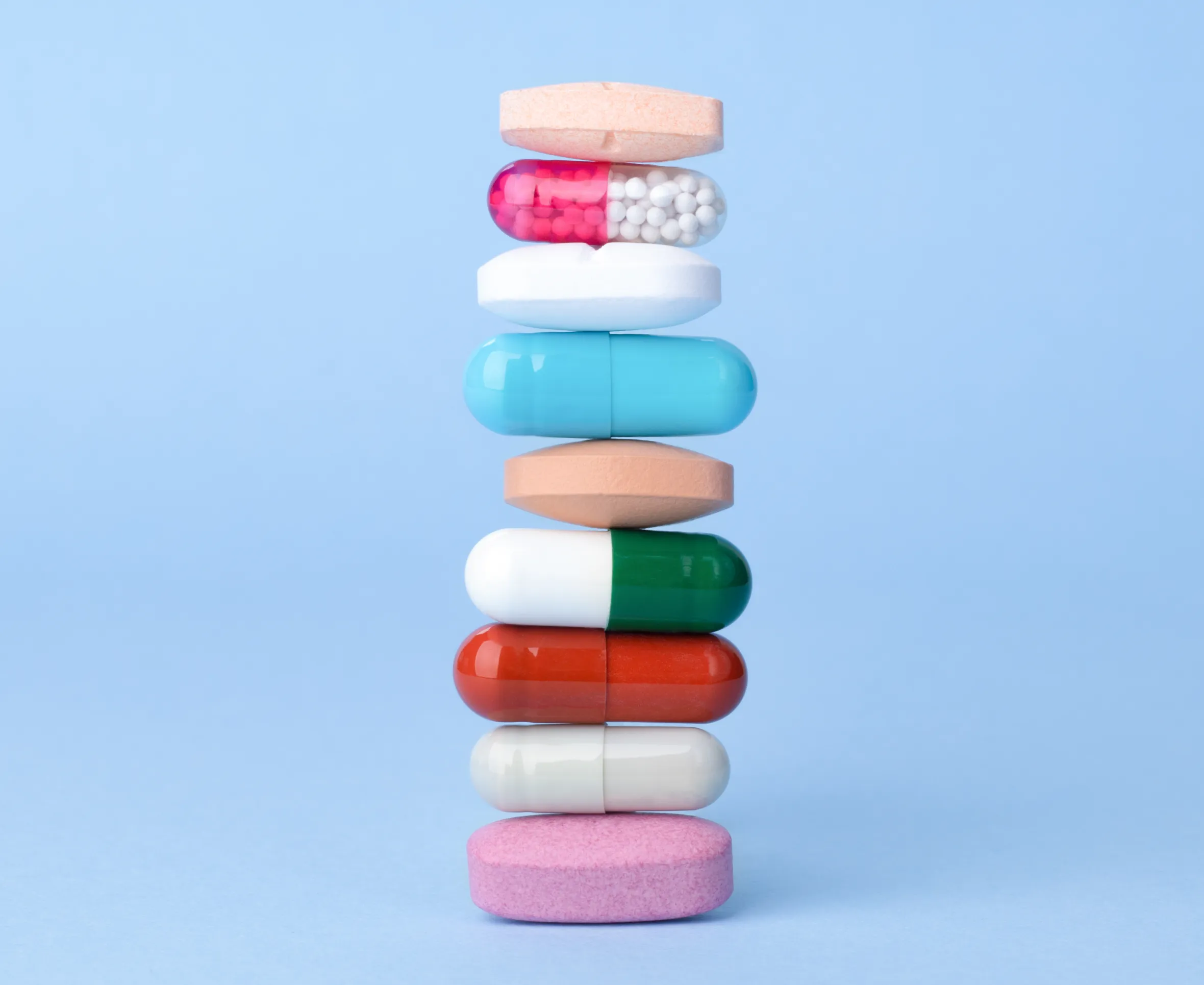 Assorted pharmaceutical drugs balancing on each other, conceptional idea . Blue background with copyspace