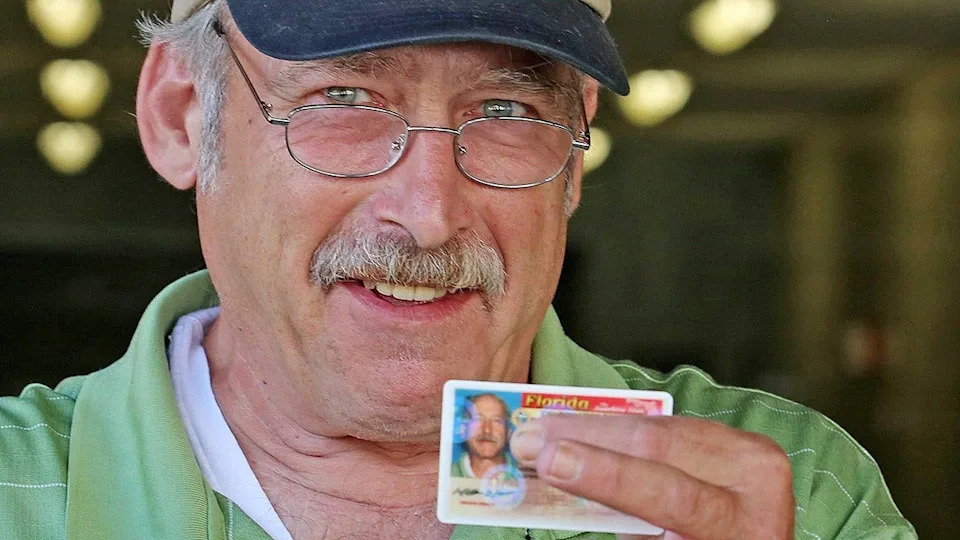 Benjaman Kyle placing fingers over his real name on Florida ID card