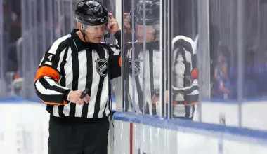 NHL referee Wes McCauley (4) puts on a headset for a video review of a disallowed Islanders goal during the third period between the New York Islanders and the Columbus Blue Jackets at UBS Arena.