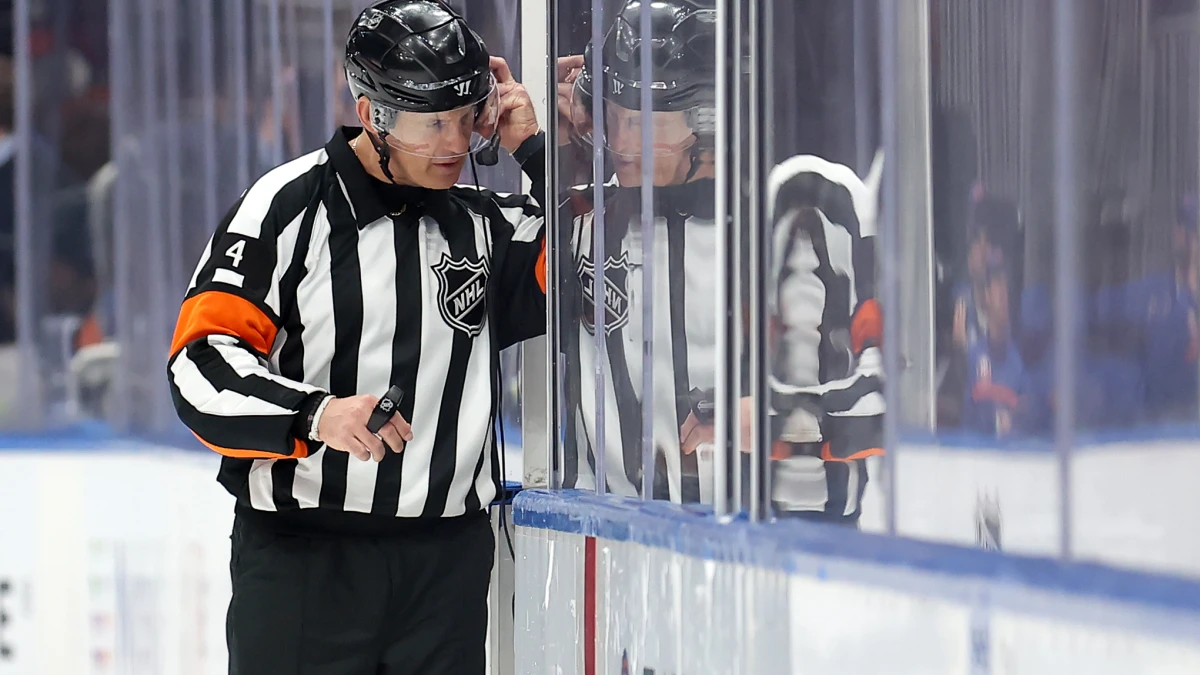 NHL referee Wes McCauley (4) puts on a headset for a video review of a disallowed Islanders goal during the third period between the New York Islanders and the Columbus Blue Jackets at UBS Arena.