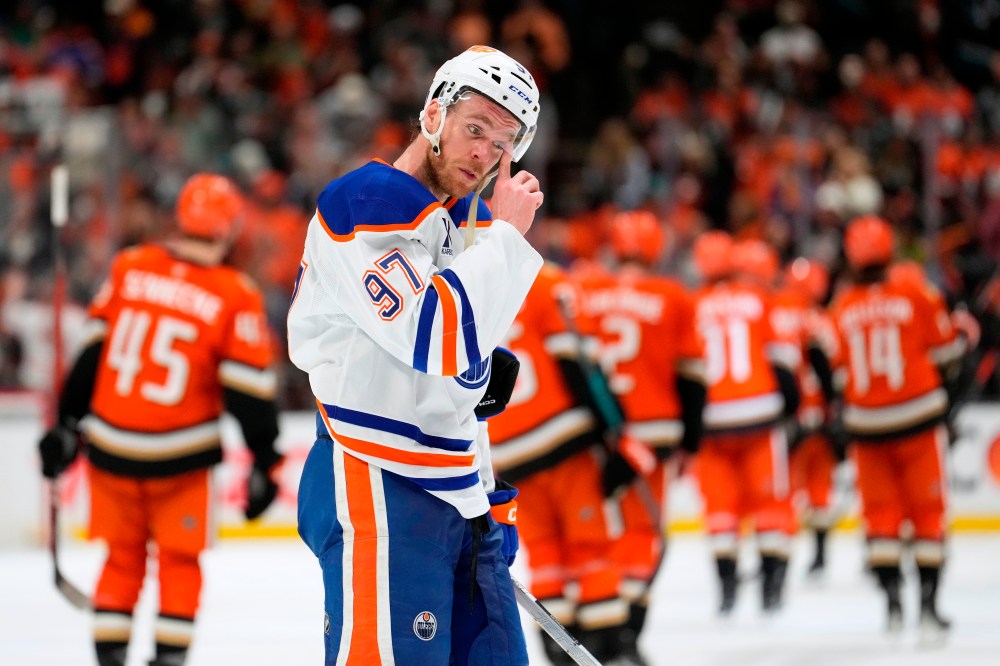 Edmonton Oilers center Connor McDavid wipes his visor as members of the Anaheim Ducks celebrate after they were defeated in Game 6 in the first round of the NHL hockey Stanley Cup playoffs series Thursday, April 30, 2026, in Anaheim, Calif. (AP Photo/Mark J. Terrill)