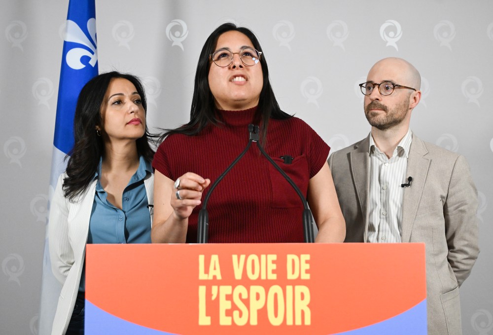 Quebec Solidaire co-spokespersons Ruba Ghazal, left, and Sol Zanetti, right, look on as the party's economy critic Alejandra Zaga Mendez speaks during a news conference at the party's convention in Montreal, Saturday, May 9, 2026. THE CANADIAN PRESS/Graham Hughes