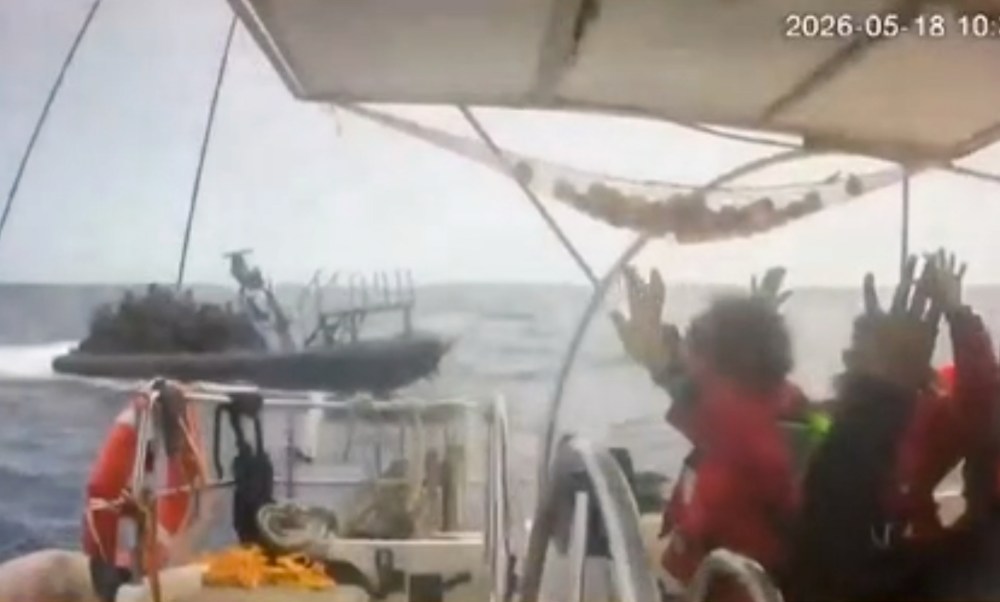 This grab from CCTV footage shows activists aboard a flotilla boat with their hands in the air as a boat approaches one of more than 50 vessels that departed from the port of Marmaris, Turkey, last week in what organizers of the Global Sumud Flotilla described as the final leg of their planned journey to Gaza's shores, in international waters Monday, May 18, 2026. (Global Sumud Flotilla via AP)