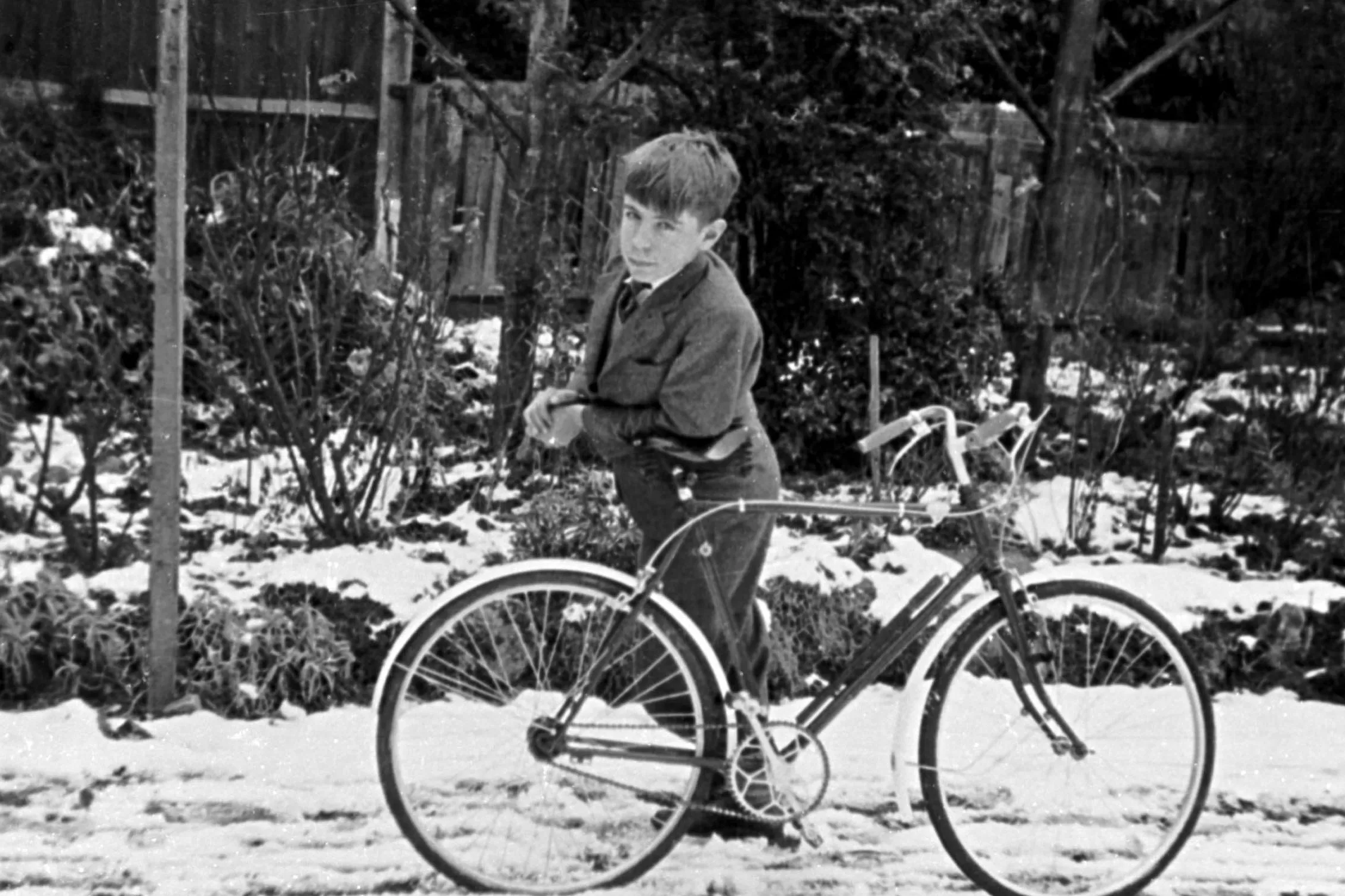 A 12-year-old Stephen Hawking in a garden in St Albans, leaning on his bicycle.