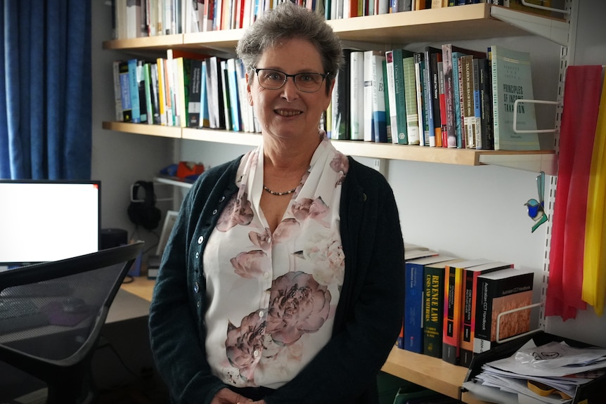 A woman standing in an office with books shelves in background