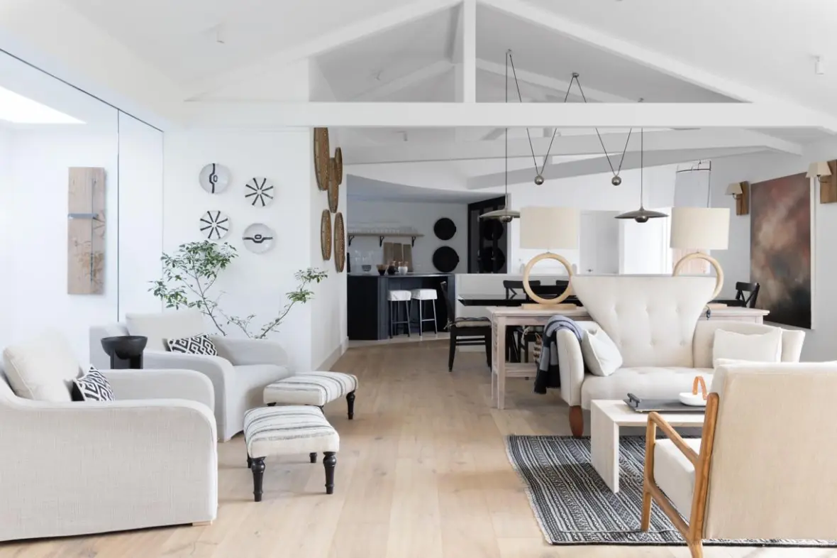 A bright open-plan living room with a kitchen in the background.