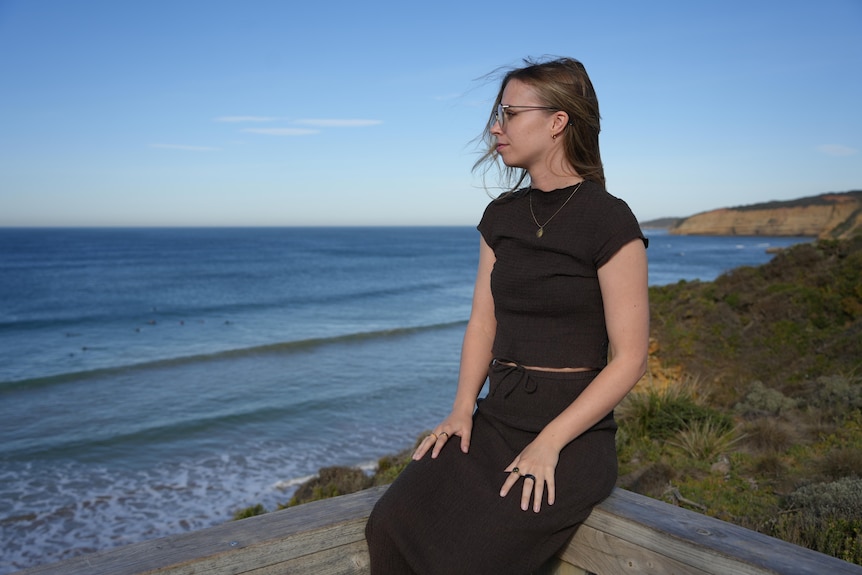 A woman stares pensively out at the ocean.