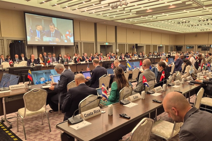 A room full of people looking towards a projector screen.