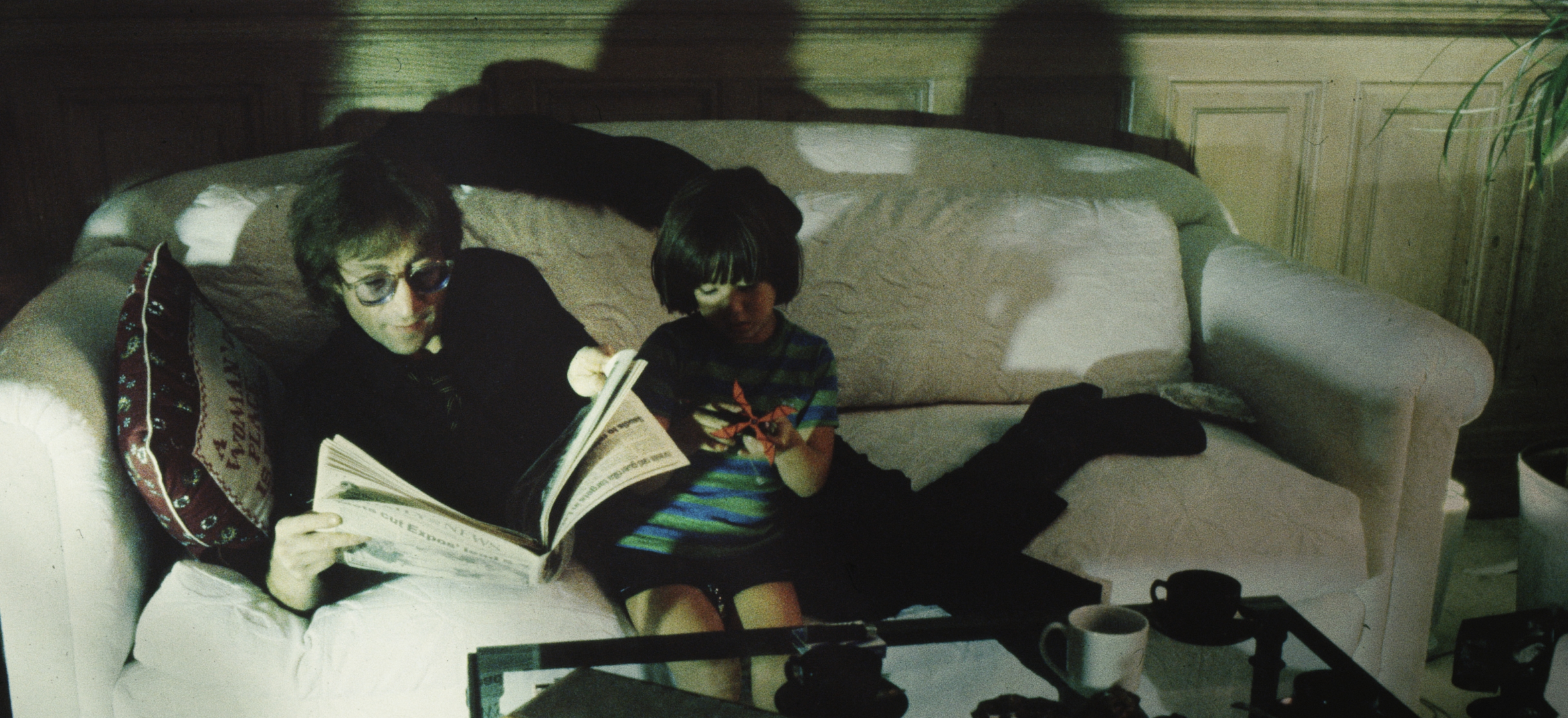 John Lennon and Sean Lennon relaxing on a couch.