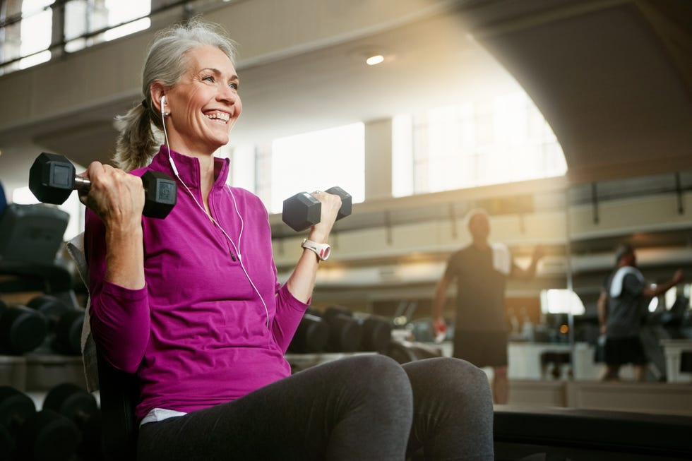 Live, laugh, love, lift portrait of a happy senior woman working out with weights at the gym