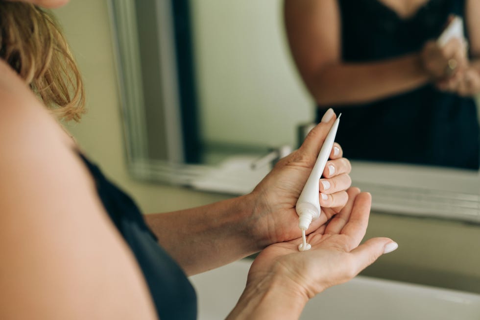 how to reduce skin cancer risk: woman squeezing face cream into her hand.