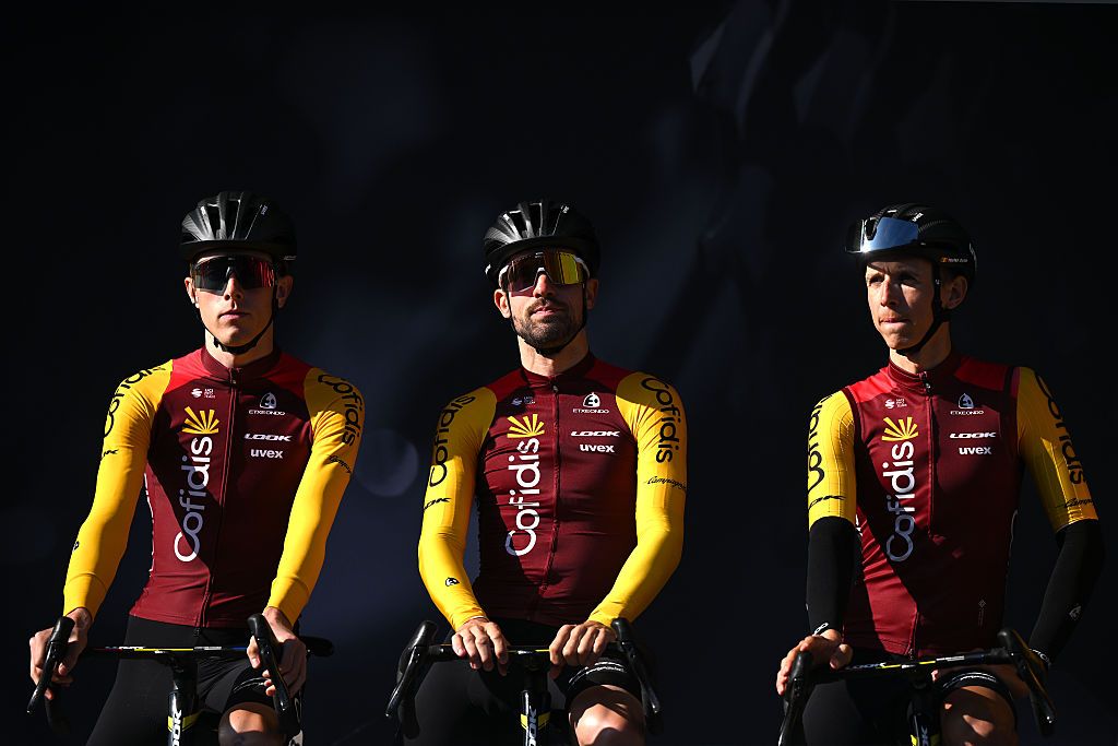 Three Cofidis riders against a moody, dark background