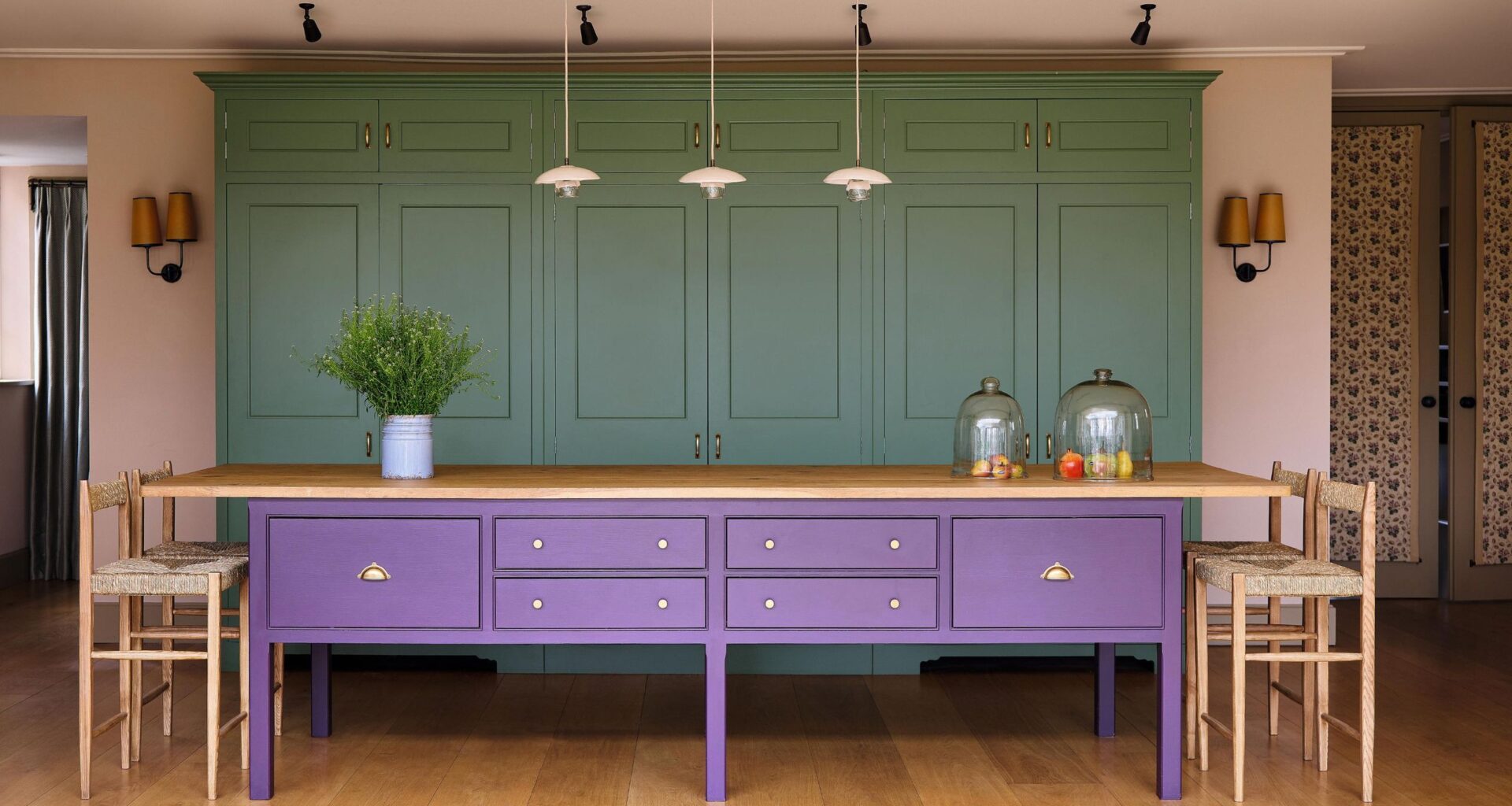 a green and kitchen with a large purple island with oak kitchen steels and a trio of pendant lights above